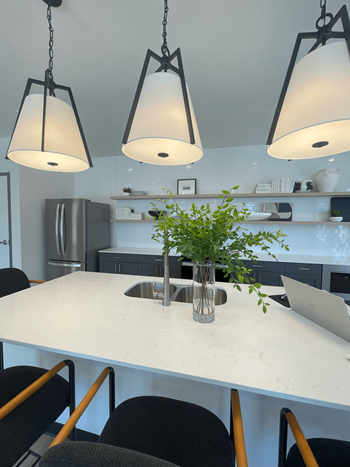 A kitchen with a table and chairs and three hanging lights.